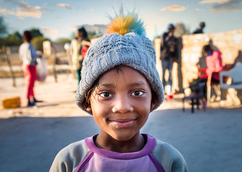 Portrait of a smiling african girl in the village with the family at sunset