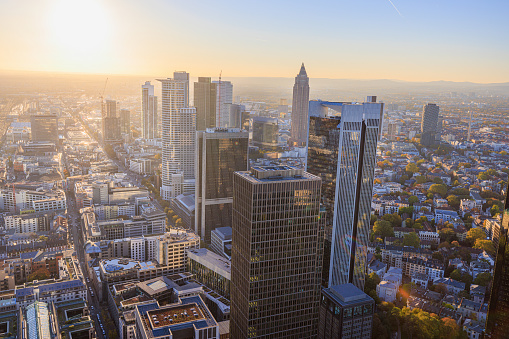 Aerial view on financial district corporate skyscraper in Frankfurt am Main, office buildings towers rising high among lower architecture, illuminated with sunlight at dawn