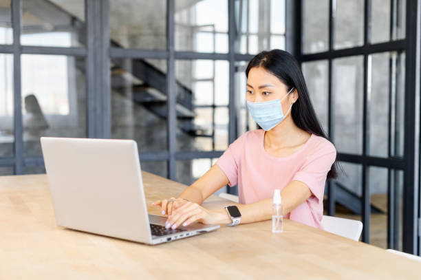 istock Young Asian female office worker in face mask 1406897960
