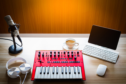 midi keyboard, computer, headphone, microphone on desk. music production equipments background concept