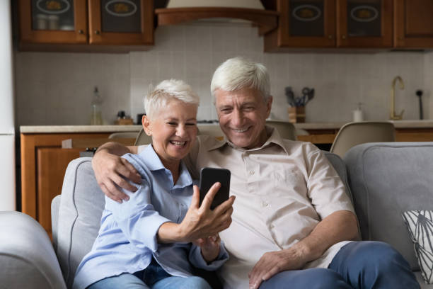 istock Loving aged couple hug on sofa shoot selfie on cellphone 1406899719