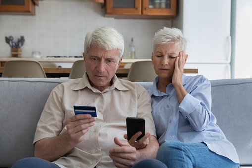 Shocked aged couple overspending money online using credit card phone