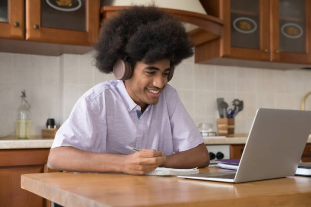 istock Joyful African high school student guy wearing wireless headphones 1406899848