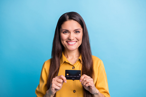 Photo portrait of business woman smiling holding debit plastic card isolated on vibrant blue color background.