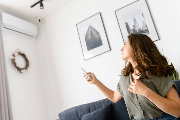 istock Attractive curly young woman switching on air conditioner 1406904698