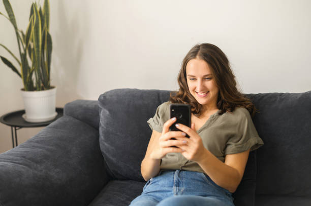 istock Attractive curly young woman using smartphone at home 1406904726
