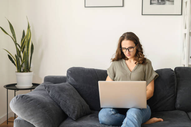 istock Attractive curly young woman using laptop at home 1406904736
