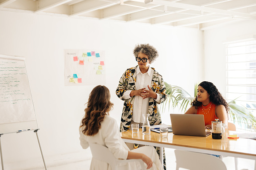 Senior businesswoman having a discussion with her colleagues in a boardroom. Group of businesswomen sharing creative ideas during a meeting. Businesswomen working together in an all-female startup.