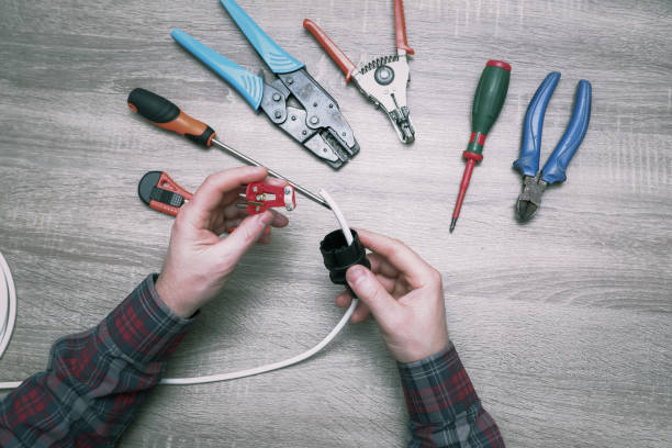 istock A male electrician changes the plug on an electric wire. Working with electrical tools. Stripper, crimp, screwdriver, wire cutters. Electrician connecting wires 1406909056