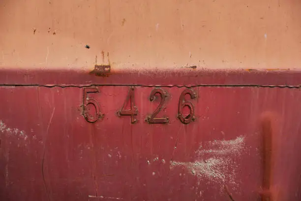 Photo of Rusty metal surface of red colour numbers on a background Old metal container