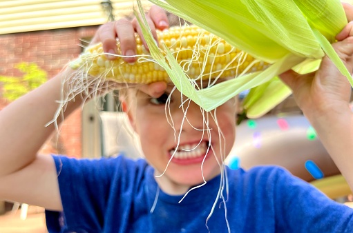 Young boy being silly with corn on the cob