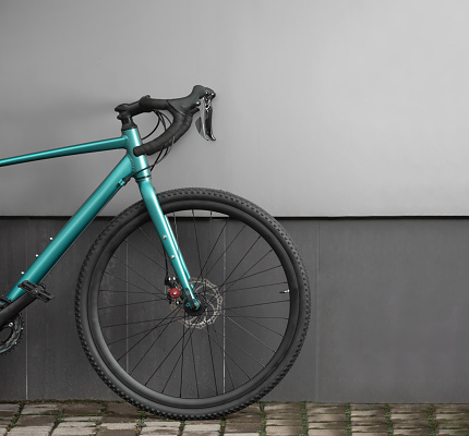 Front part of gravel bike on grey wall background. Modern brand new bicycle for cross country.