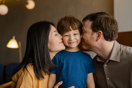 Mother and father kiss their child's cheeks tenderly while enjoy the holidays trip.