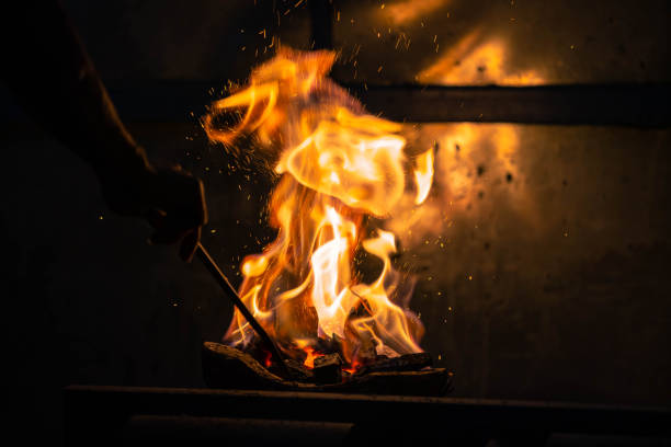istock Hand adjust burning charcoal for cooking with flame and fire spark on dark background 1406913337