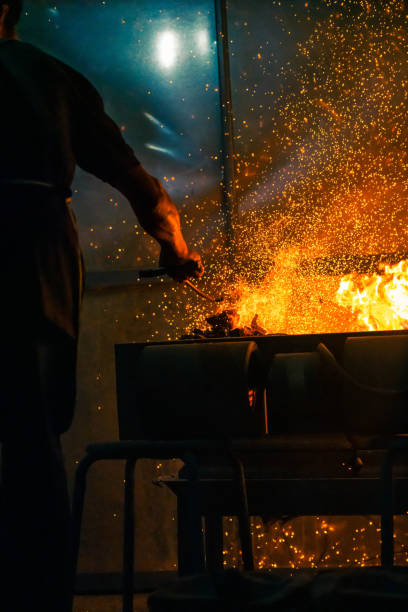 istock Hand adjust burning charcoal for cooking with flame and fire spark on dark background 1406913378