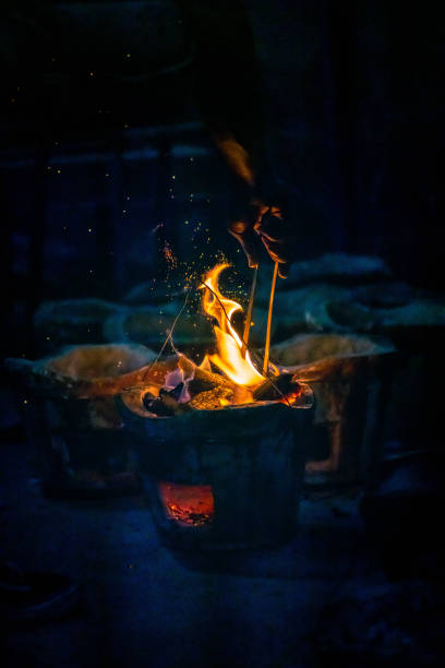 istock Hand adjust burning charcoal for cooking with flame and fire spark on dark background 1406913431