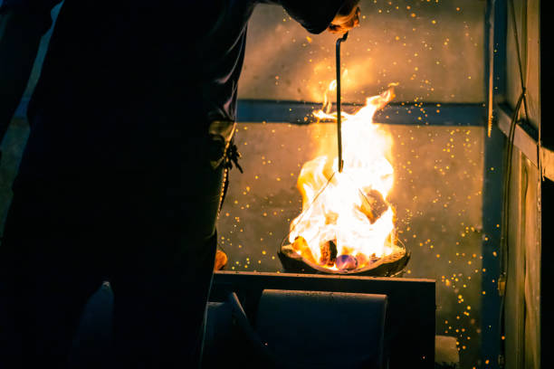 istock Hand adjust burning charcoal for cooking with flame and fire spark on dark background 1406913546