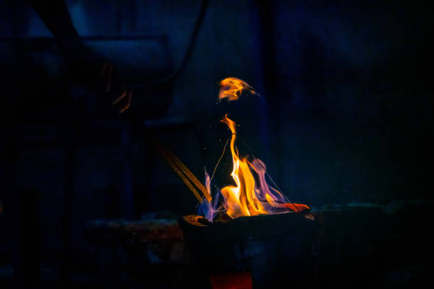 Hand adjust burning charcoal for cooking with flame and fire spark on dark background