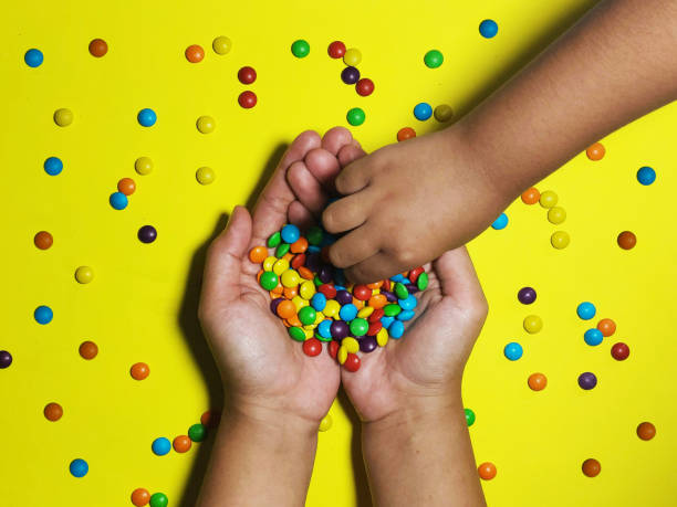 istock hands sharing colorful candy with background yellow 1406914913