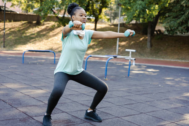 istock Afro young woman training with dumbbells outdoors 1406915216