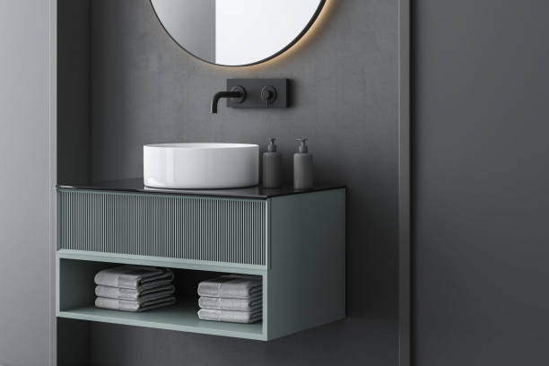 Close up of white sink with oval mirror hanging in on dark wall, modern green cabinet stock photo