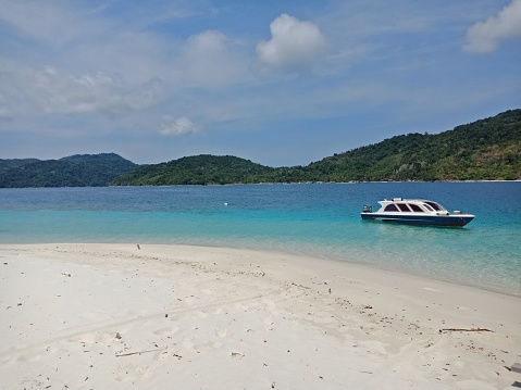 White speed boat leaning in sandy beach at tenggiling island
