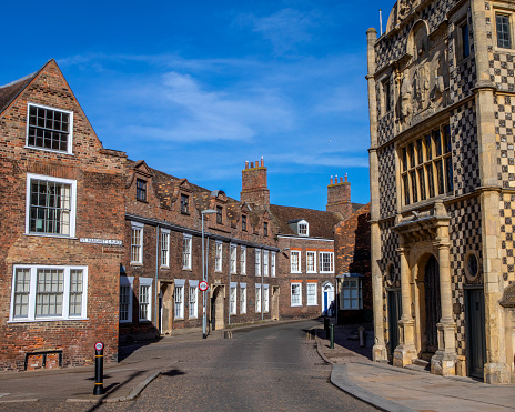 A view of the beautiful Georgian architecture of Queen Street in the market town of Kings Lynn in Norfolk, UK. The facade of Kings Lynn Town Hall is on the right-handside.