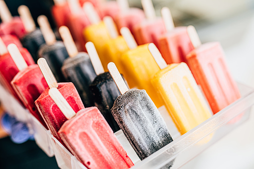 Close up shot of delicious and colorful fruit ice creams on wooden sticks.