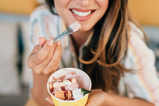 Beautiful and happy brown hair woman enjoying in eating delicious handmade rolled ice cream.
