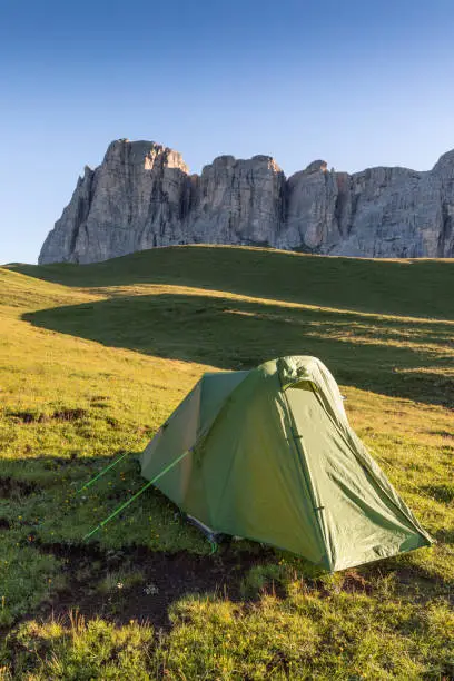 A glowing tent in the mountains under a blue morningsky. Sunrise and mountains in the background. Summer landscape. Panorama
Bright tourist tent in the mountains nature.
