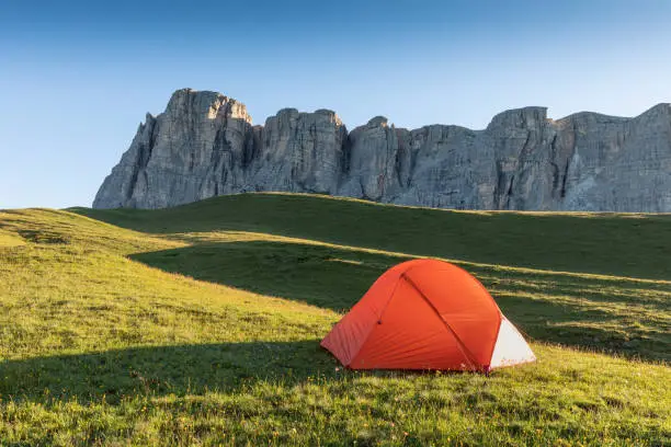 A glowing tent in the mountains under a blue morningsky. Sunrise and mountains in the background. Summer landscape. Panorama
Bright tourist tent in the mountains nature.