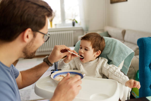 istock Caring single father spoon feeding his beautiful son 1406924147