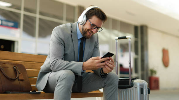 istock Businessman using phone while waiting for a train at train station 1406924362