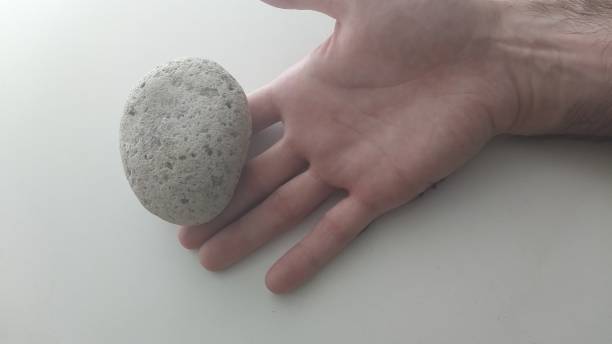 istock stone standing in male hand, on white background, 1406924822