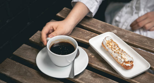 istock Cup of coffee and eclair on a wooden table close-up. 1406926521