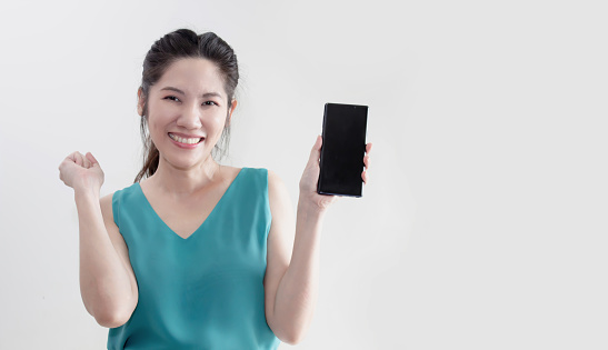 Asian beautiful woman  raise arm up and holding smartphone and smile with happiness  or glad to communicate promotion