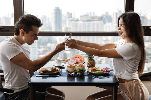 istock Cheerful couple playfully fights with cutlery during the breakfast 1406927906
