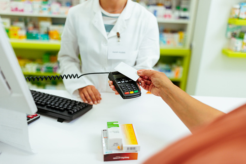 Unrecognizable person making a contactless credit card payment at drugstore