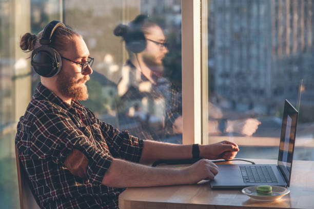 istock A man with a beard works at a computer, sitting in the office by the window. 1406930335