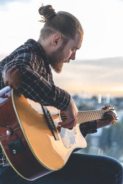 istock A man with a beard plays the acoustic guitar. 1406930348