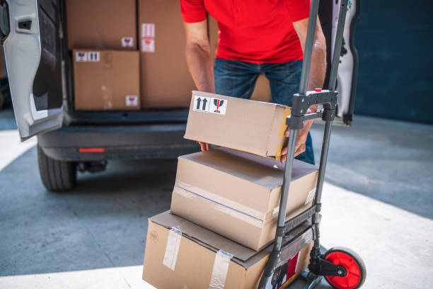 istock Unrecognizable delivery person loading parcels on push cart. 1406930485