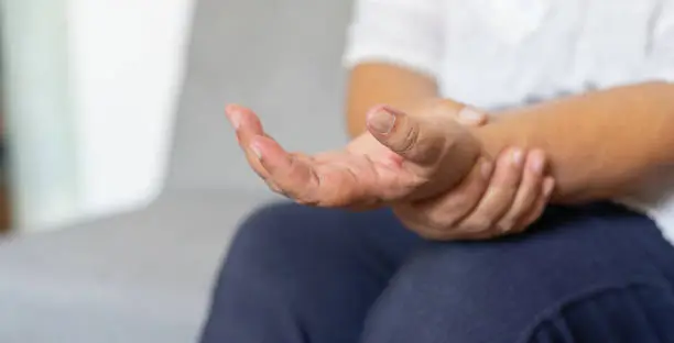 Photo of close up senior woman massage on hand to relief pain from hard working for treatment about carpal tunnel syndrome and chronic illness health care concept