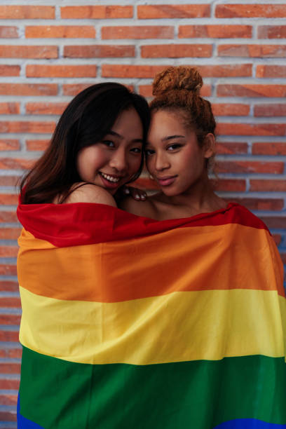 istock Lesbian couple hugging wrapped in a LGBT flag 1406932049