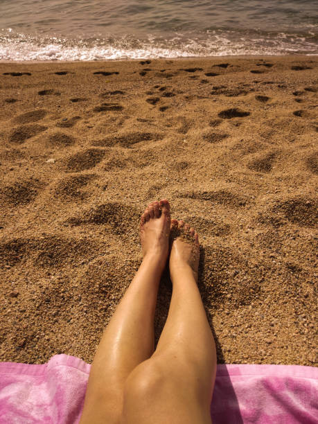 istock tanned legs sunbathing on the beach 1406932241