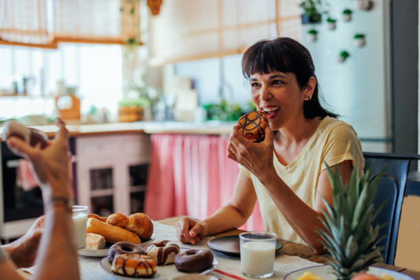 istock Middle aged couple eating donuts at home 1406933027