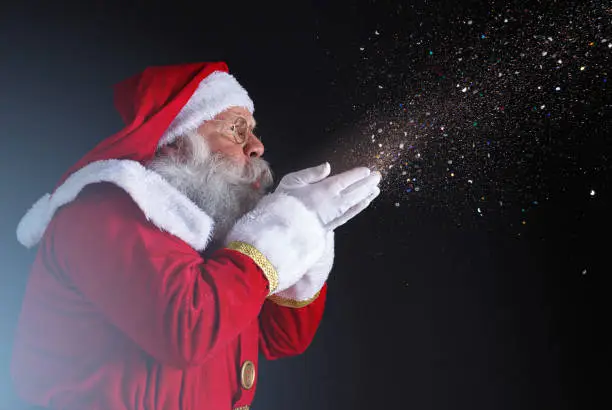 Photo of Christmastime traditions. Santa blowing snowflakes.