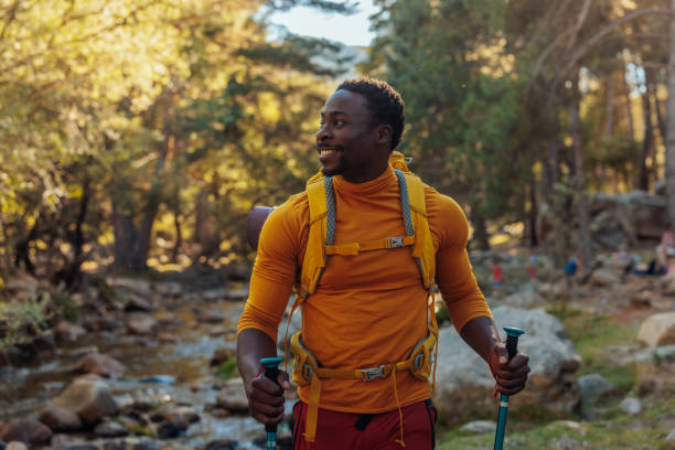 Cheerful hiker next to mountain stream A cheerful African American hiker is standing next to a mountain stream in the forest hiking stock pictures, royalty-free photos & images