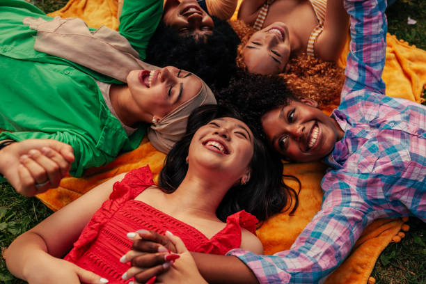istock Cheerful girls lying in circle on grass holding hands 1406934719