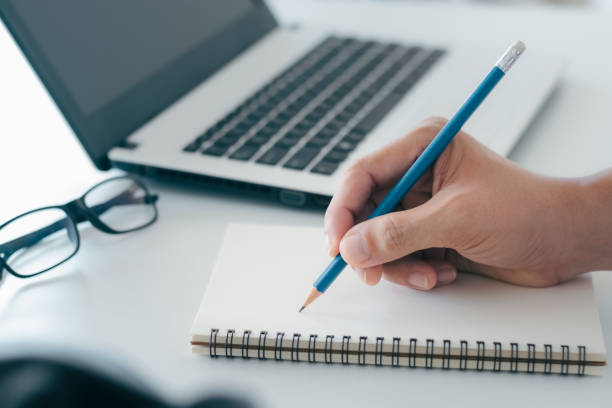 istock Businessman taking notes Summarize the meeting online with laptop, working alone, sitting at your desk. Working from home, close-up hands. 1406934832