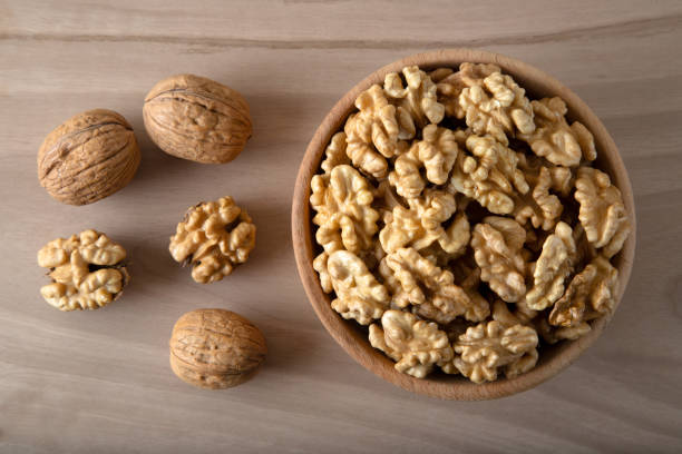istock Peeled walnuts and whole walnuts on wooden background 1406939140